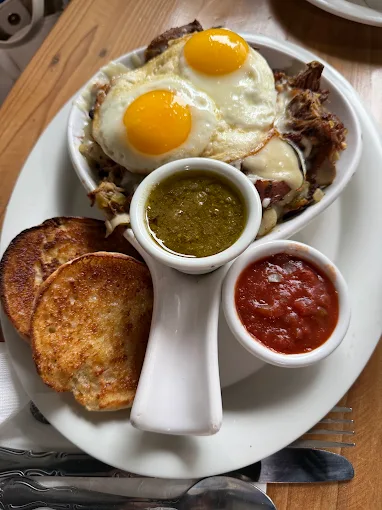 Carnitas hash topped with two eggs and salsas